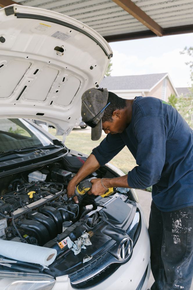Wichita mobile mechanic working under a hood at a carport